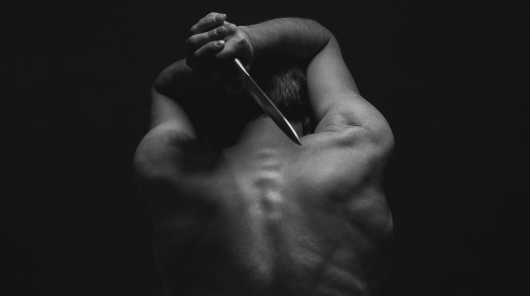 Άτομο κρατά πίσω από την πλάτη του μαχαίρι