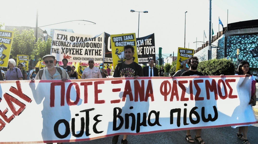 Δίκη Χρυσής Αυγής: Άτομα κρατούν πανό που γράφει «Ποτέ ξανά φασισμός» έξω από το Εφετείο Αθηνών