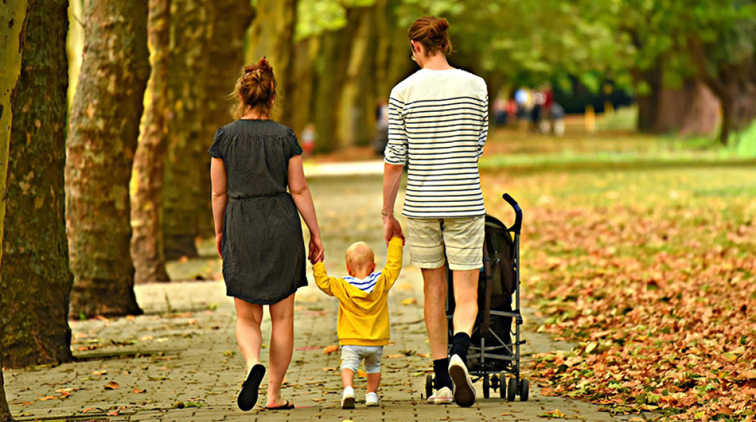 Γονείς με το παιδί τους κάνουν βόλτα σε πάρκο