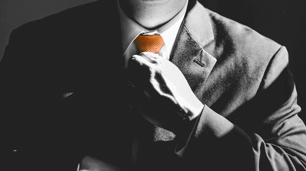 Άντρας με κοστούμι που φτιάχνει τη γραβάτα του