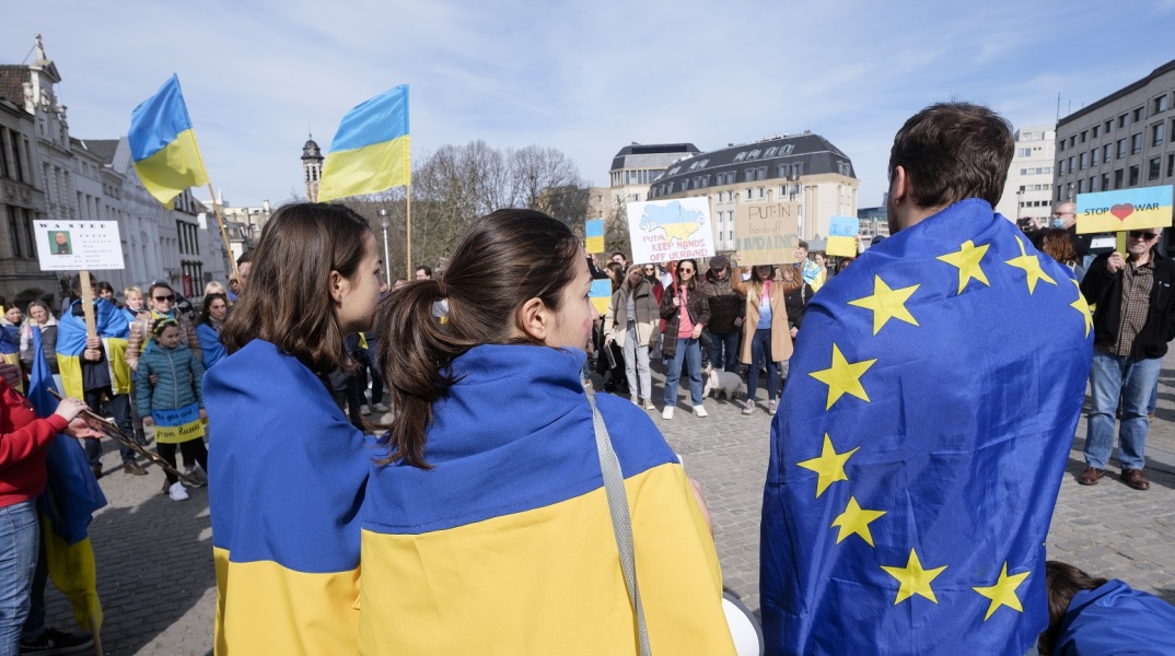 Δύο γυναίκες με τη σημαία της Ουκρανίας κι άντρας με τη σημαία της Ευρωπαϊκής Ένωσης σε πορεία