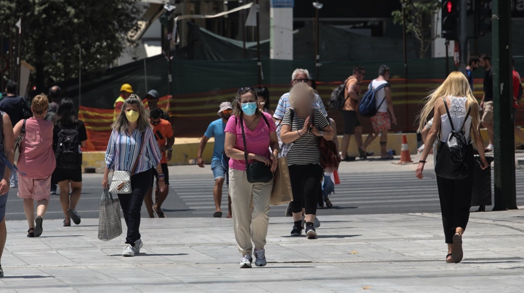 Πολίτες με μάσκα περπατούν στην πλατεία Συντάγματος