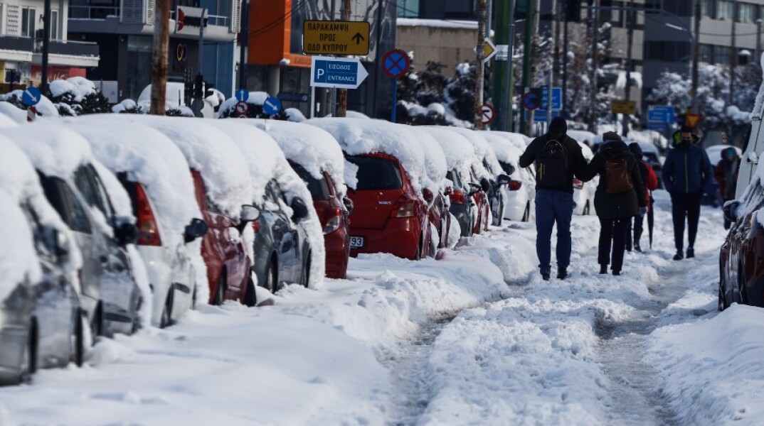 Κακοκαιρία «Ελπίδα»: Πολίτες περπατούν πάνω στη Μεσογείων λόγω του χιονιού που βρίσκεται στα πεζοδρόμια