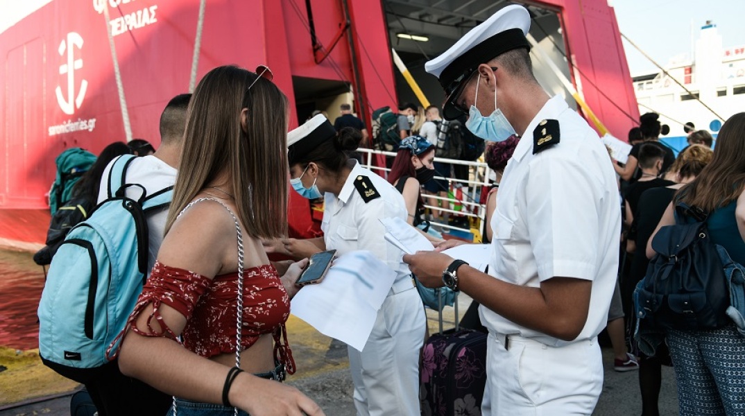 Ταξιδιώτες αναμένουν την επιβίβασή τους σε πλοίο κρατώντας στα χέρια κινητό ή έγγραφα που χρειάζονται 