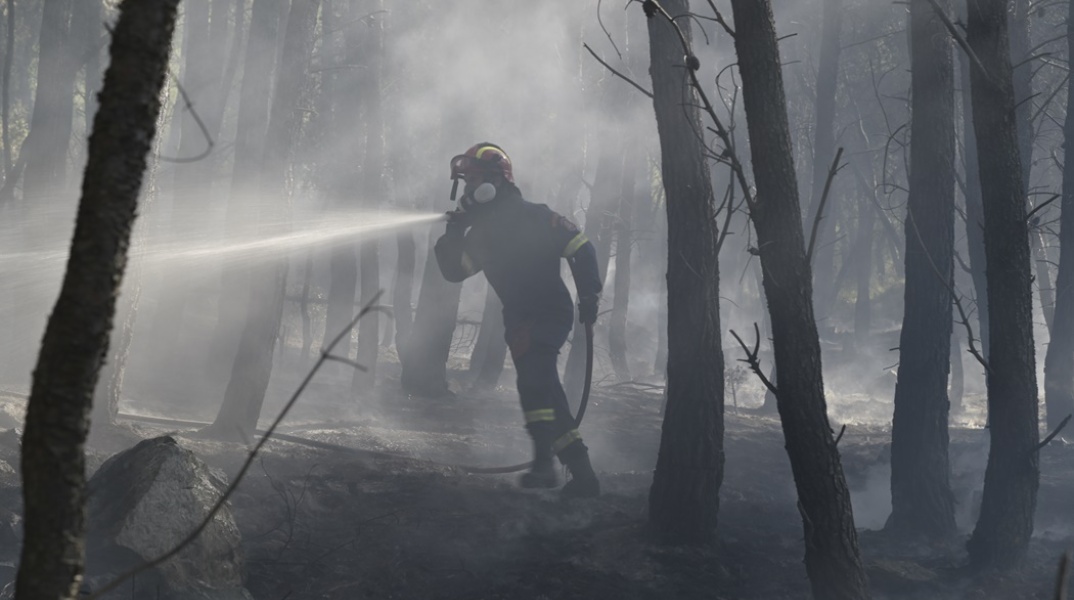 Πυροσβέστης πίσω από καπνούς από την πυρκαγιά