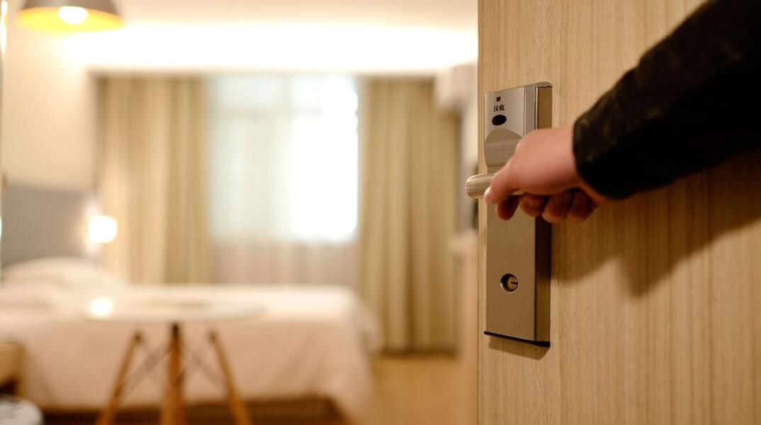 Πόρτα που ανοίγει με φόντο δωμάτιο ξενοδοχείου