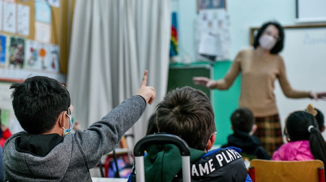Μαθητές σηκώνουν το χέρι της για να πουν μάθημα μέσα σε τάξη με δασκάλα