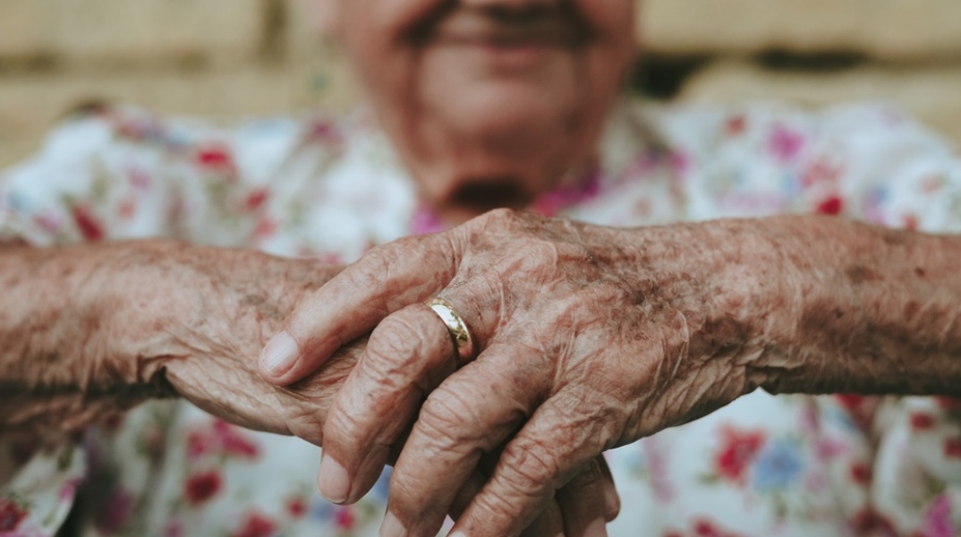 Ηλικιωμένη γυναίκα που φορά βέρα στερεώνει τα χέρια της στη μαγκούρα