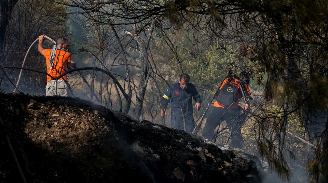 Πυροσβέστες και εθελοντές με μάνικα στα χέρια επιχειρούν για την κατάσβεση πυρκαγιάς