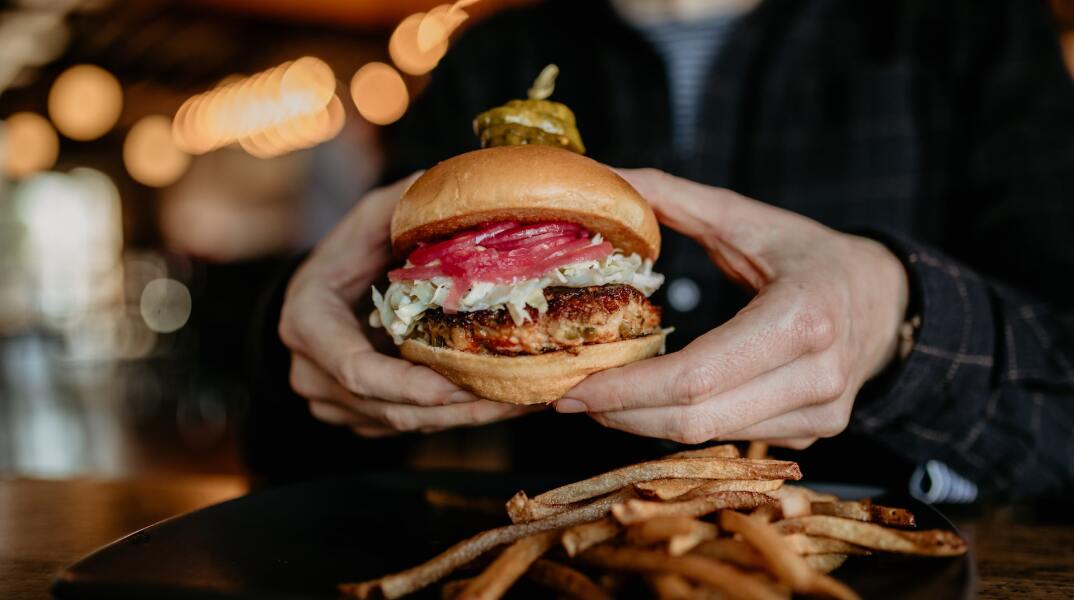 Fast Food - Burger που το κρατά μία γυναίκα και πατάτες