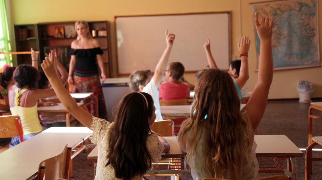 Μαθητές σηκώνουν το χέρι τους στο μάθημα μπροστά από τη δασκάλα