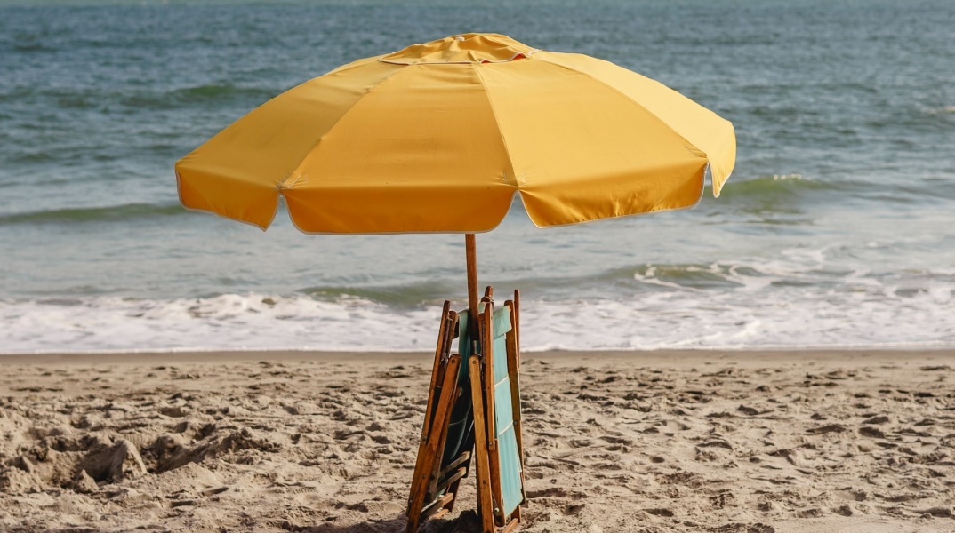 Ομπρέλα ανοιχτή σε παραλία με δύο ομπρέλες μαζεμένες
