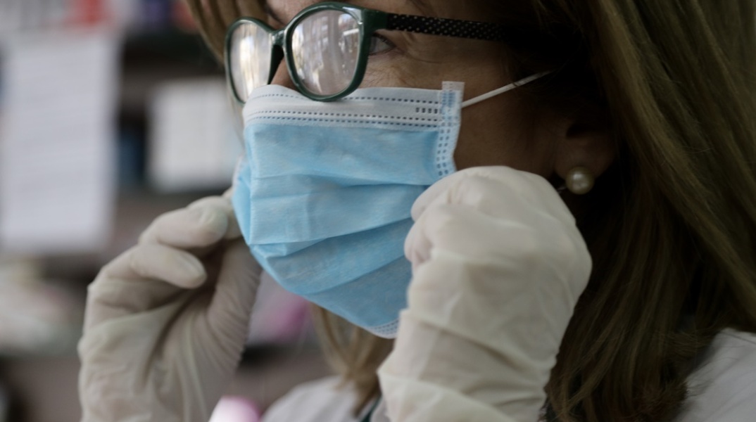 Γυναίκα με μάσκα και γάντια για την προστασία της από τη γρίπη