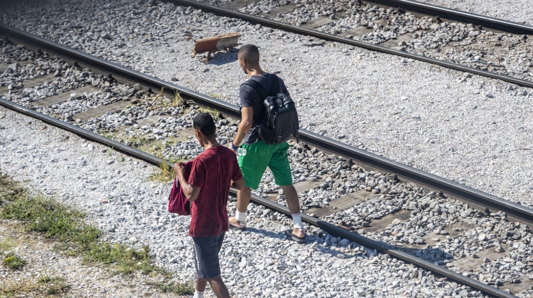 Μετανάστες περπατούν δίπλα στις γραμμές τρένου