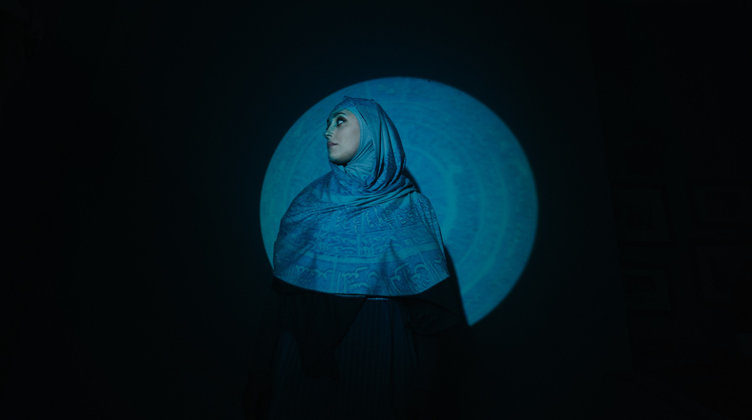 Γυναίκα που φοράει χιτζάμπ, στέκεται μπροστά από μαύρο τοίχο