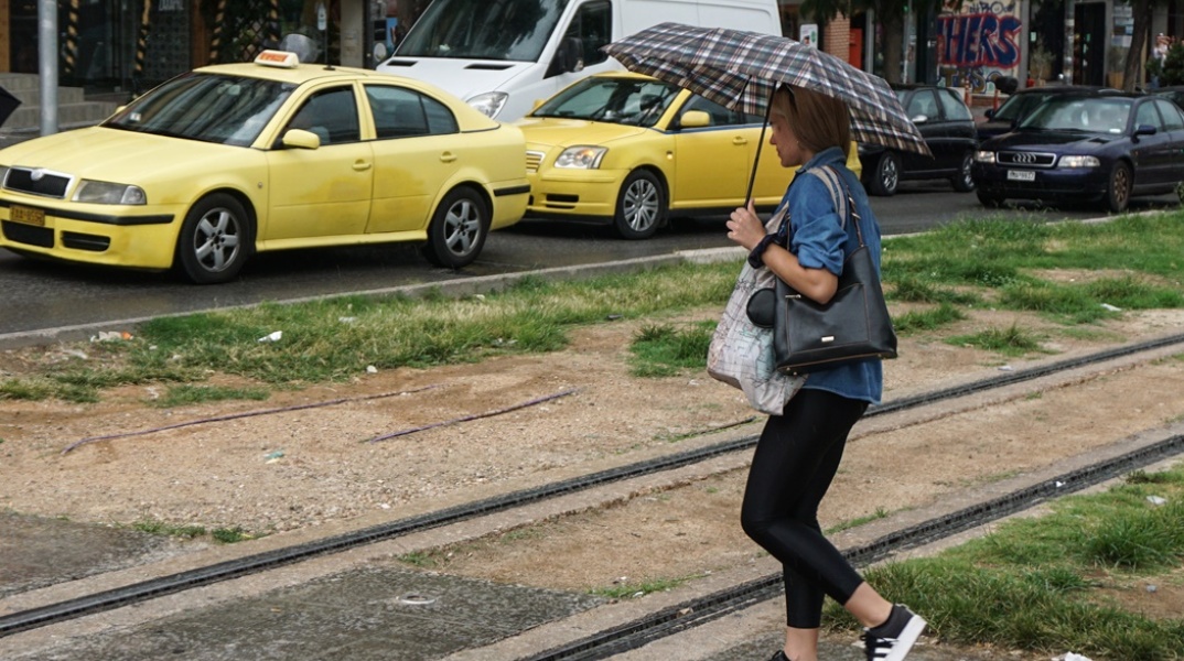 Γυναίκα με ομπρέλα περπατά σε δρόμο