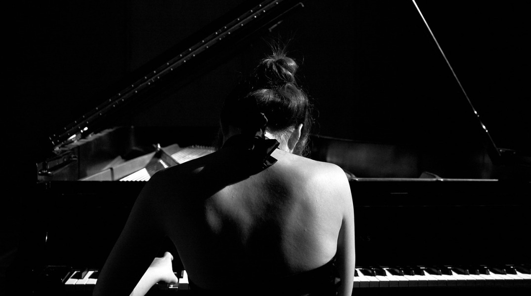 Γυναίκα παίζει πιάνο σε σκοτεινό φόντο