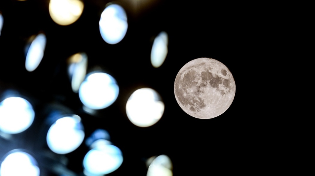 Η πανσέληνος διακρίνεται πίσω από φώτα γηπέδου