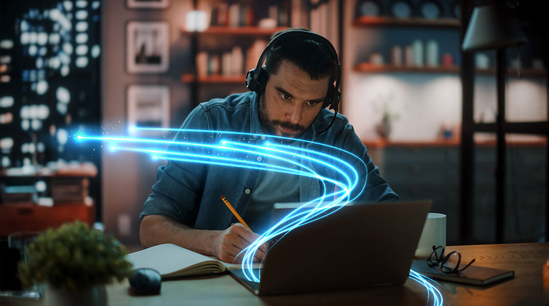 Άνδρας καθισμένος σε γραφείο με ανοιχτό laptop μπροστά του