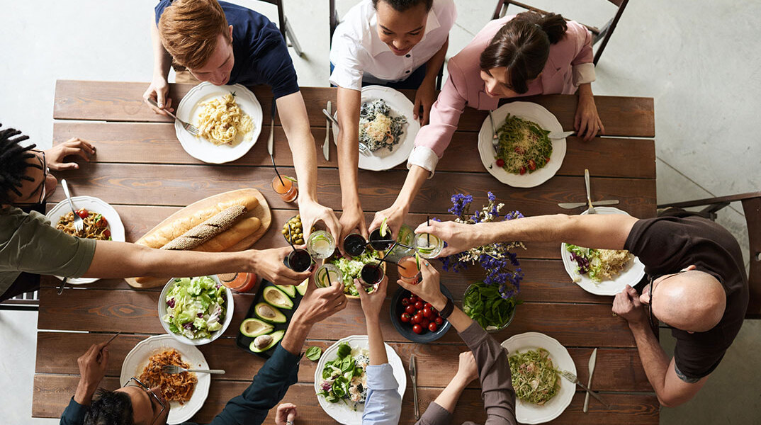 Παρέα τσουγκρίζει ποτήρια σε τραπέζι φαγητού