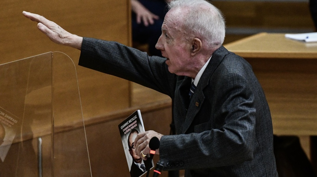 Ο Κωνσταντίνος Πλεύρης χαιρετά ναζιστικά μέσα στο δικαστήριο, κρατώντας βιβλίο του Ιωάννη Μεταξά