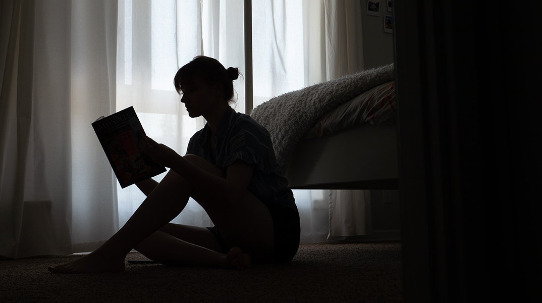 Κοπέλα καθισμένη στο πάτωμα διαβάζει βιβλίο