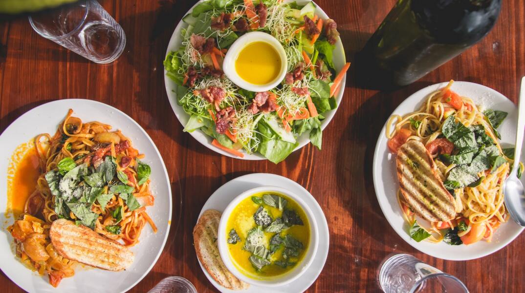 Γεύμα με σαλάτα, κρασί και δύο πιάτα στο τραπέζι