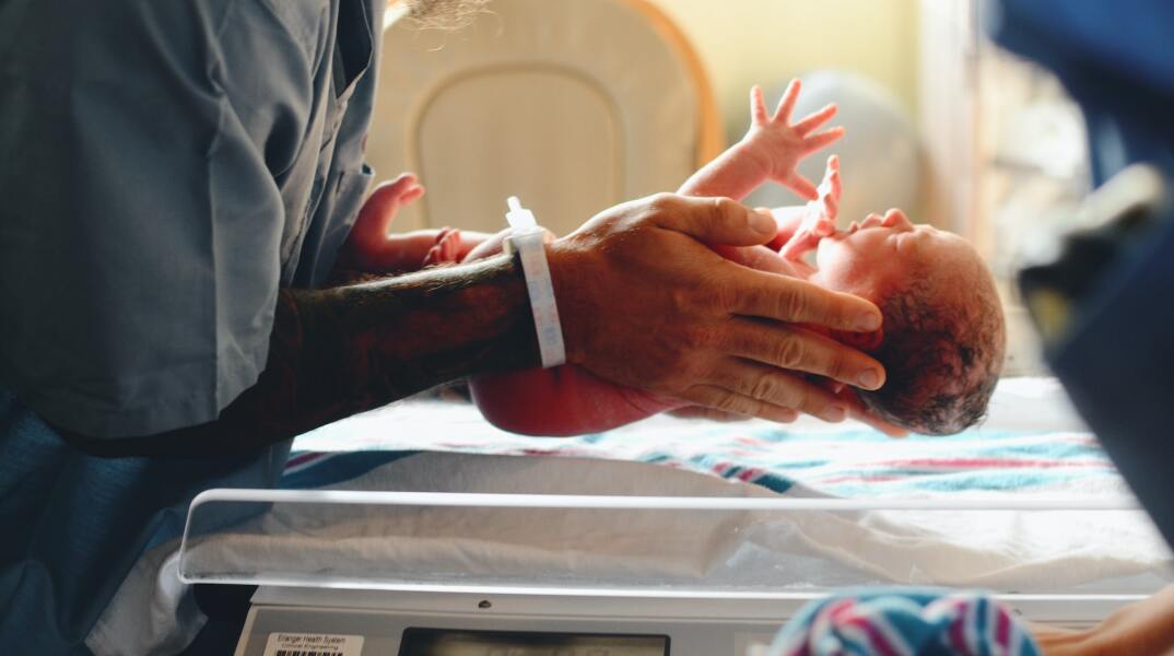 Νεογέννητο βρέφος στα χέρια ιατρικού προσωπικού ετοιμάζεται να ζυγιστεί