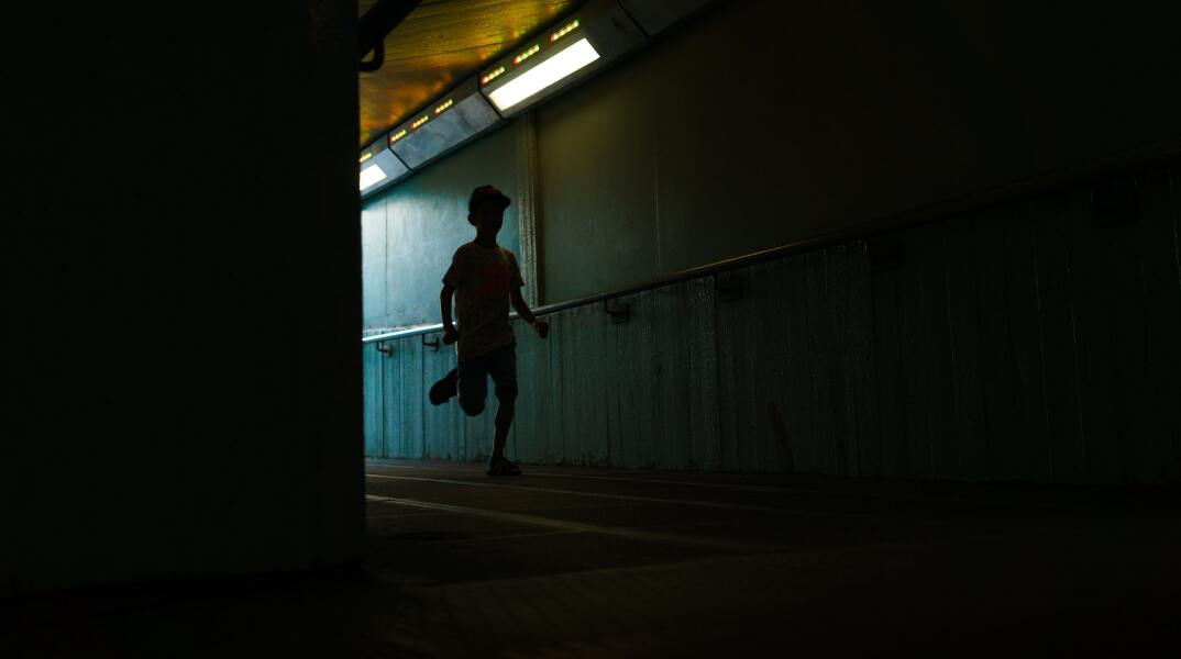 Αγόρι που τρέχει σε σκοτεινό διάδρομο