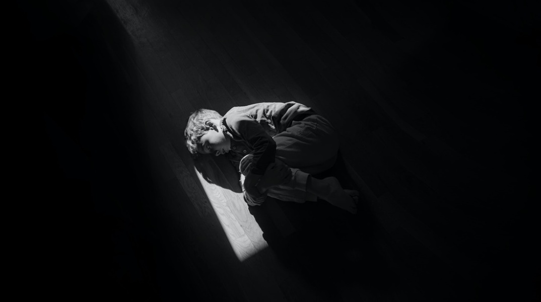 Παιδί ξαπλωμένο σε εμβρυακή στάση στο πάτωμα