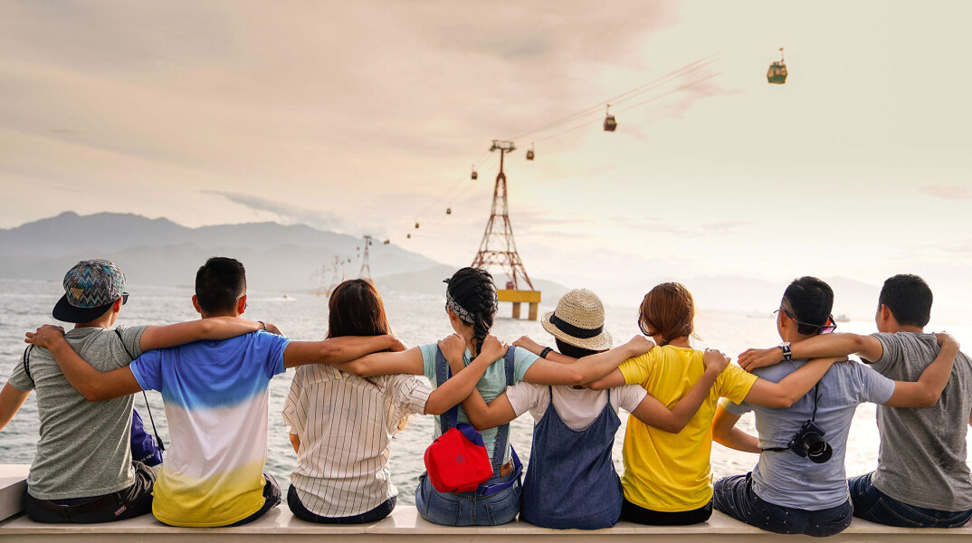 Αγόρια και κορίτσια αγκαλιασμένα, καθισμένα πλάτη προς την κάμερα