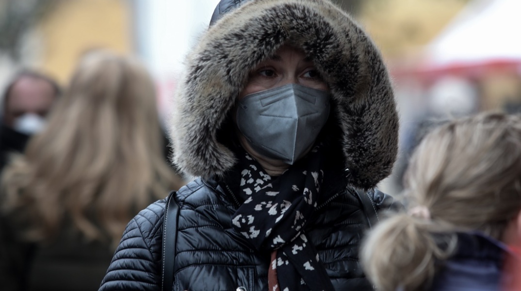 Γυναίκα με κουκούλα και κασκόλ προστατεύεται από το κρύο