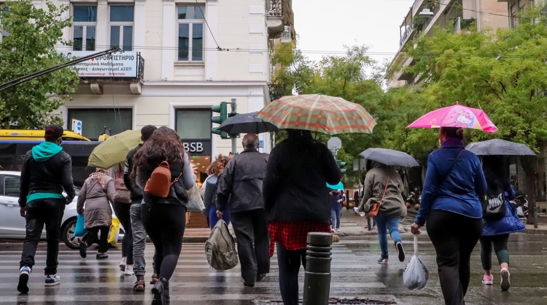 Πολίτες με ομπρέλα προστατεύονται από την καταιγίδα