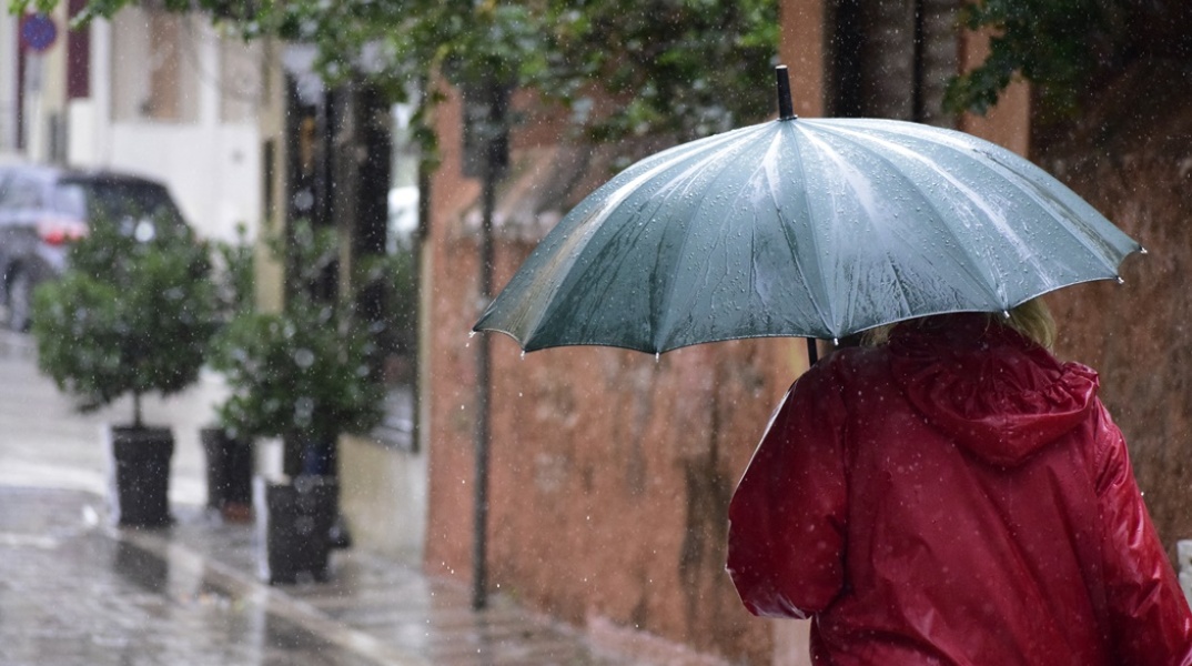 Πολίτης με ομπρέλα προσπαθεί να προστατευτεί από τη βροχή