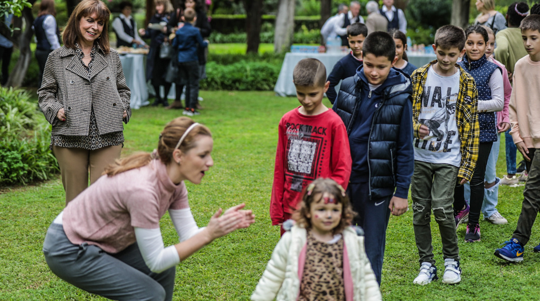 Η Κατερίνα Σακελλαροπούλου χαμογελά βλέποντας τα παιδιά του Χωριού SOS Βάρης να παίζουν στον κήπο του Προεδρικού Μεγάρου