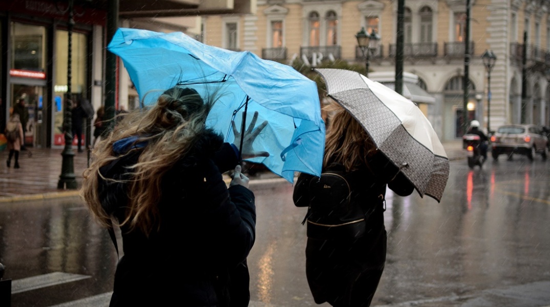 Γυναίκες κρατούν ομπρέλες για να προστατευτούν από καταιγίδα και τις παίρνει ο αέρας