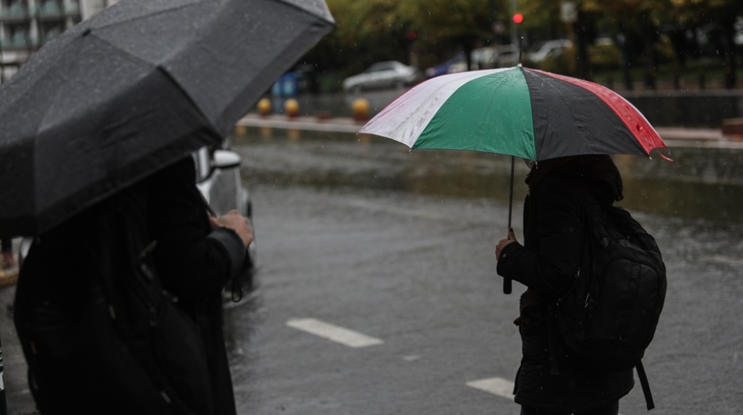 Άνδρας κρατά ομπρέλα περπατώντας στον δρόμο για να προστατευτεί από καταιγίδα