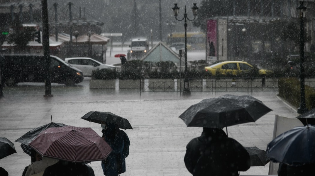 Πολίτες με ομπρέλες για την προστασία τους από την καταιγίδα στο κέντρο της Αθήνας
