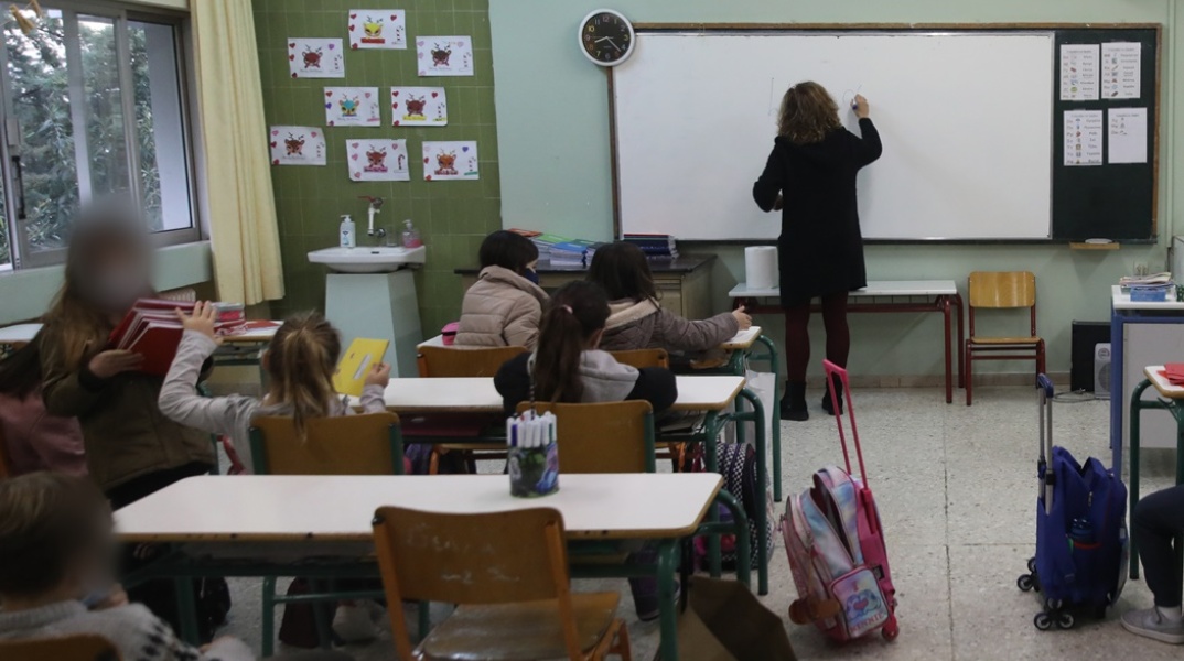 Δασκάλα μπροστά από τον πίνακα διδάσκει σε μαθητές δημοτικού