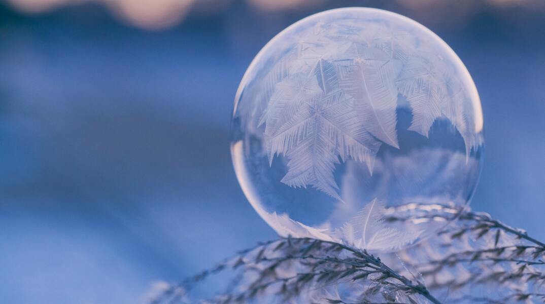Γυάλινη μπάλα με πούπουλα πάνω σε χιονισμένο κλαδί