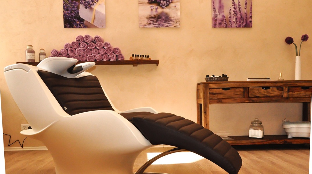 Χώρος με αναπαυτική καρέκλα και πετσέτες σε γήινα χρώματα που παραπέμπει σε κέντρο αισθητικής