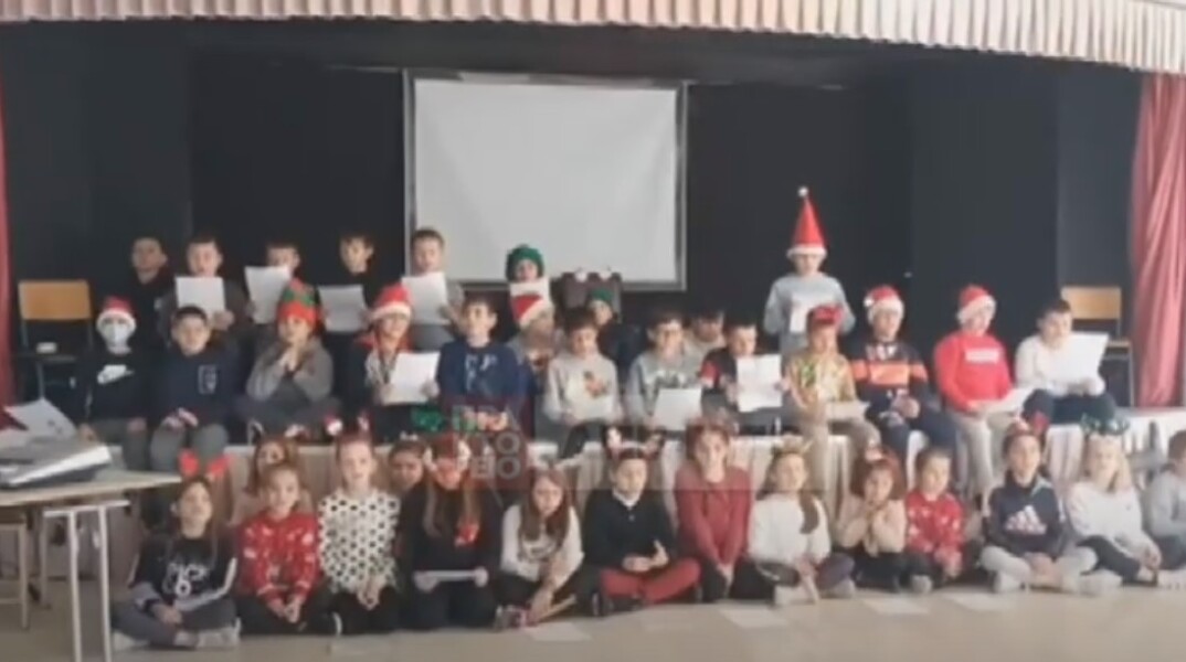 Μαθητές με χριστουγεννιάτικα καπέλα τραγουδούν το ένα δίπλα στο άλλο