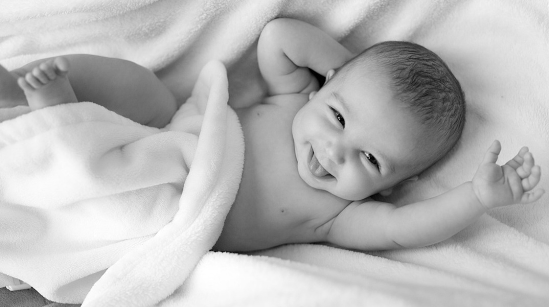 Μωρό γελά τυλιγμένο σε σεντόνια