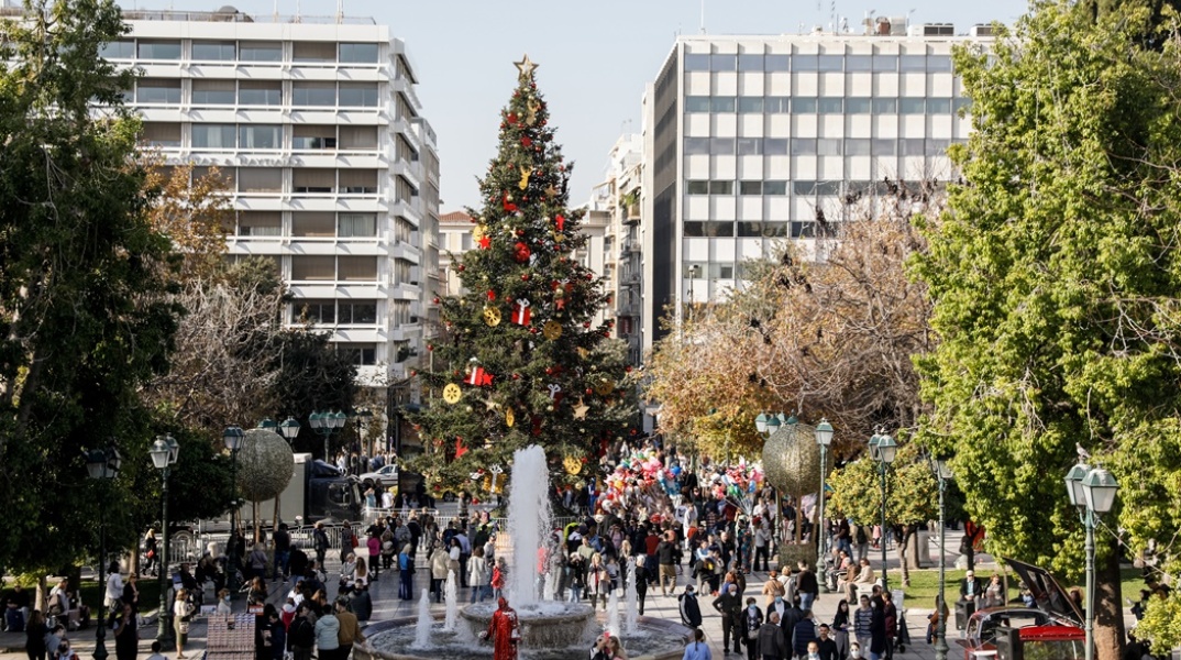 Πλήθος κόσμου στην πλατεία Συντάγματος περνά και φωτογραφίζεται κάτω από το χριστουγεννιάτικο δέντρο