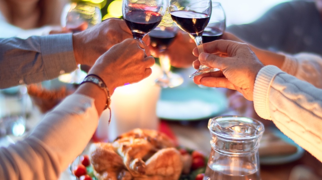 Άτομα τσουγκρίζουν τα ποτήρια με το κρασί τους στο χριστουγεννιάτικο τραπέζι