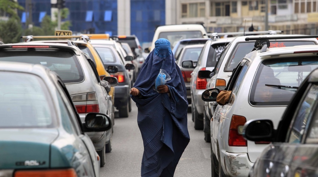Γυναίκα στο Αφγανιστάν περπατά ανάμεσα σε αυτοκίνητα