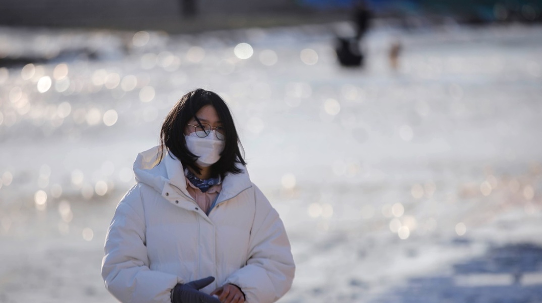 Γυναίκα στην Κίνα φορά μάσκα προστασίας από τον κορωνοϊό