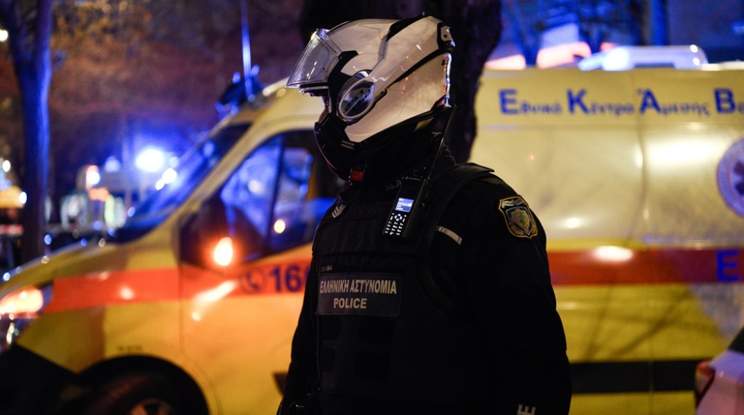 Αστυνομικός με κράνος μπροστά από ασθενοφόρο του ΕΚΑΒ