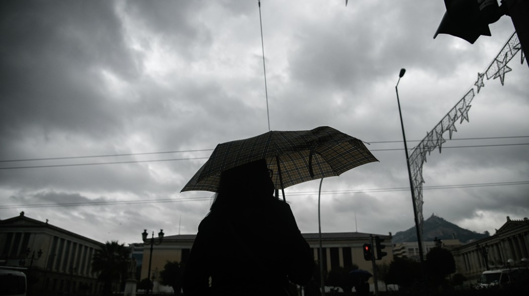 Γυναίκα με ομπρέλα προστατεύεται από την καλοκαιρινή βροχή