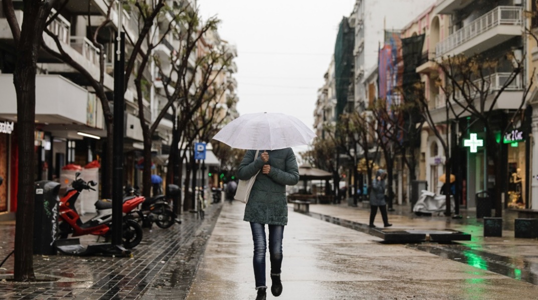 Καταιγίδα στη Θεσσαλονίκη - Γυναίκα κρατά ομπρέλα υπό βροχή